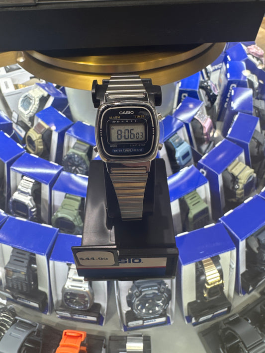 Digital watch on a stand with multiple watches in blue boxes in the background