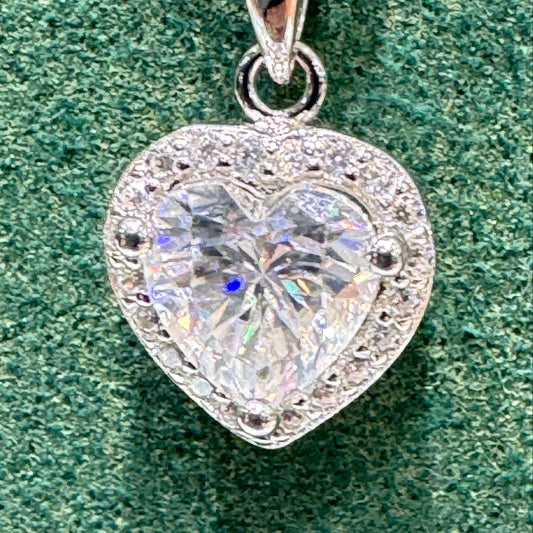 Heart-shaped diamond pendant on a green fabric background