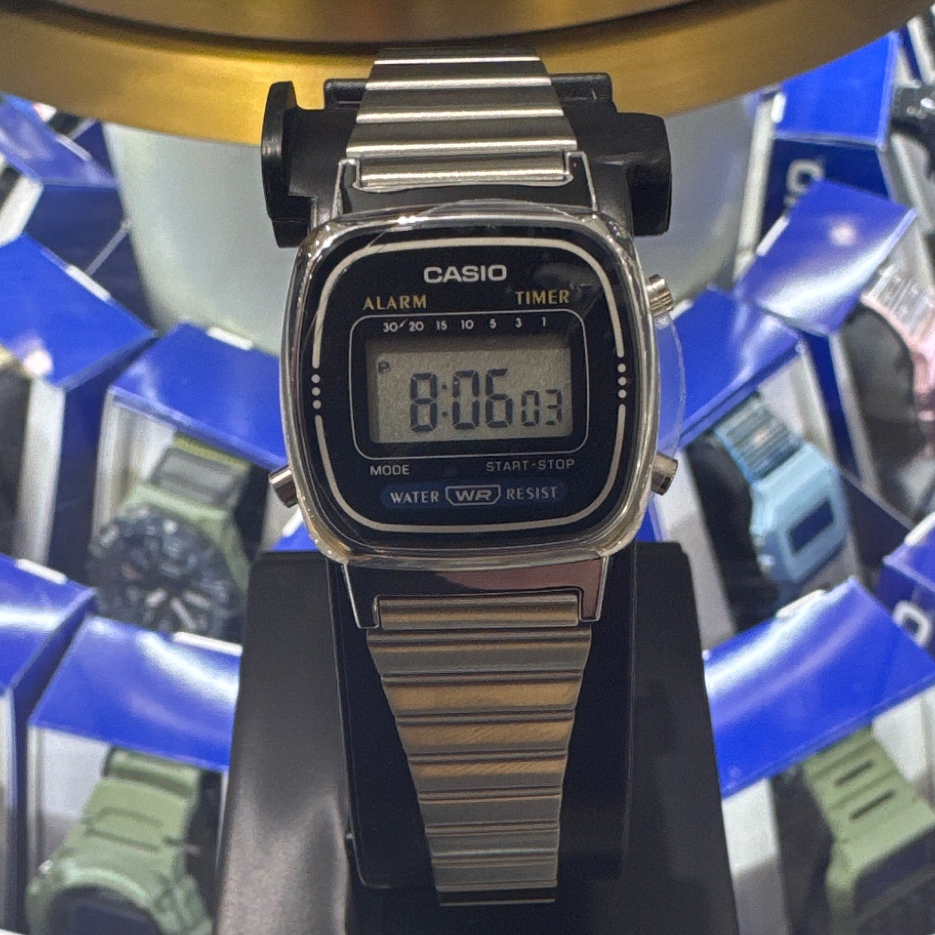 Casio digital watch on a stand with a blue and gold background