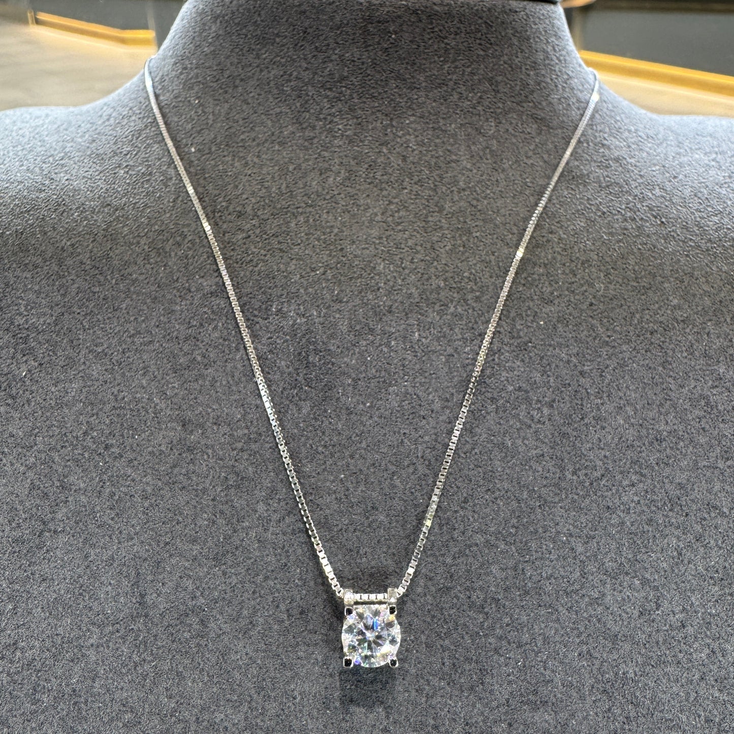 Silver necklace with a diamond pendant on a mannequin bust.