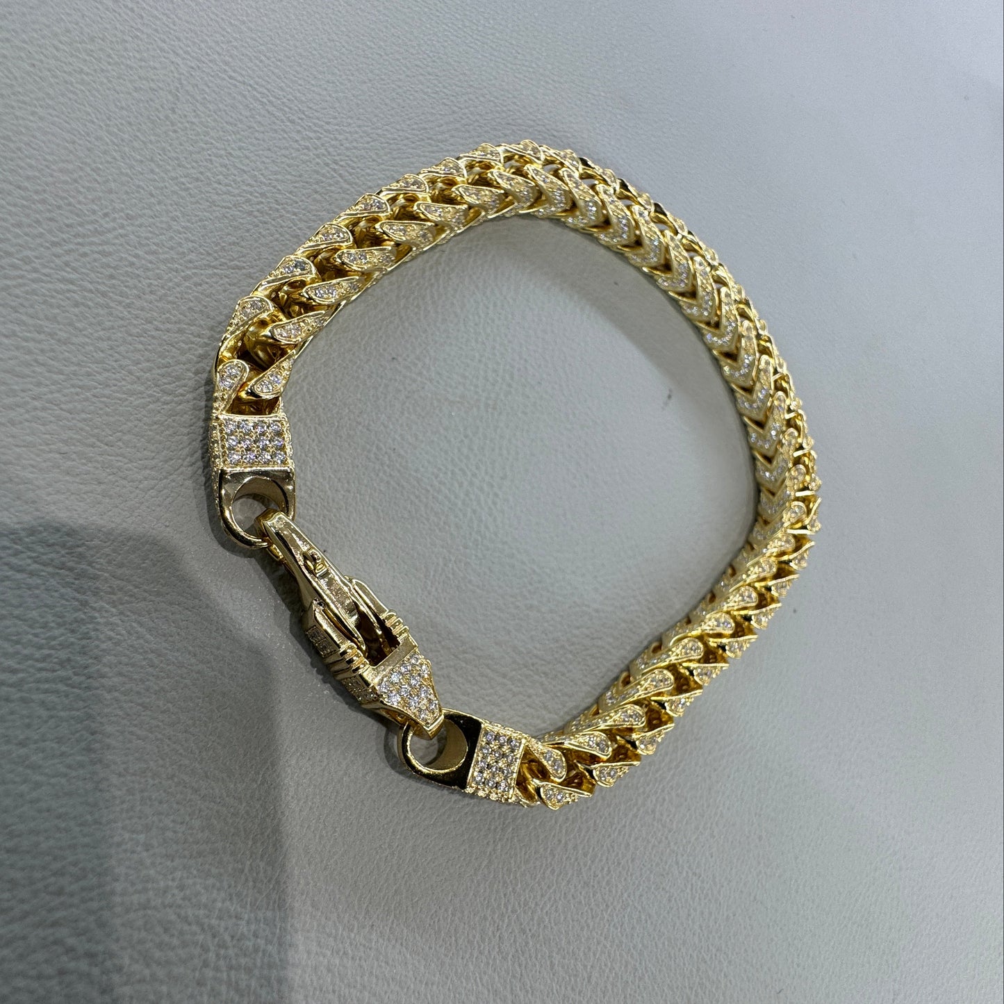 Gold bracelet with diamond accents on a light gray surface