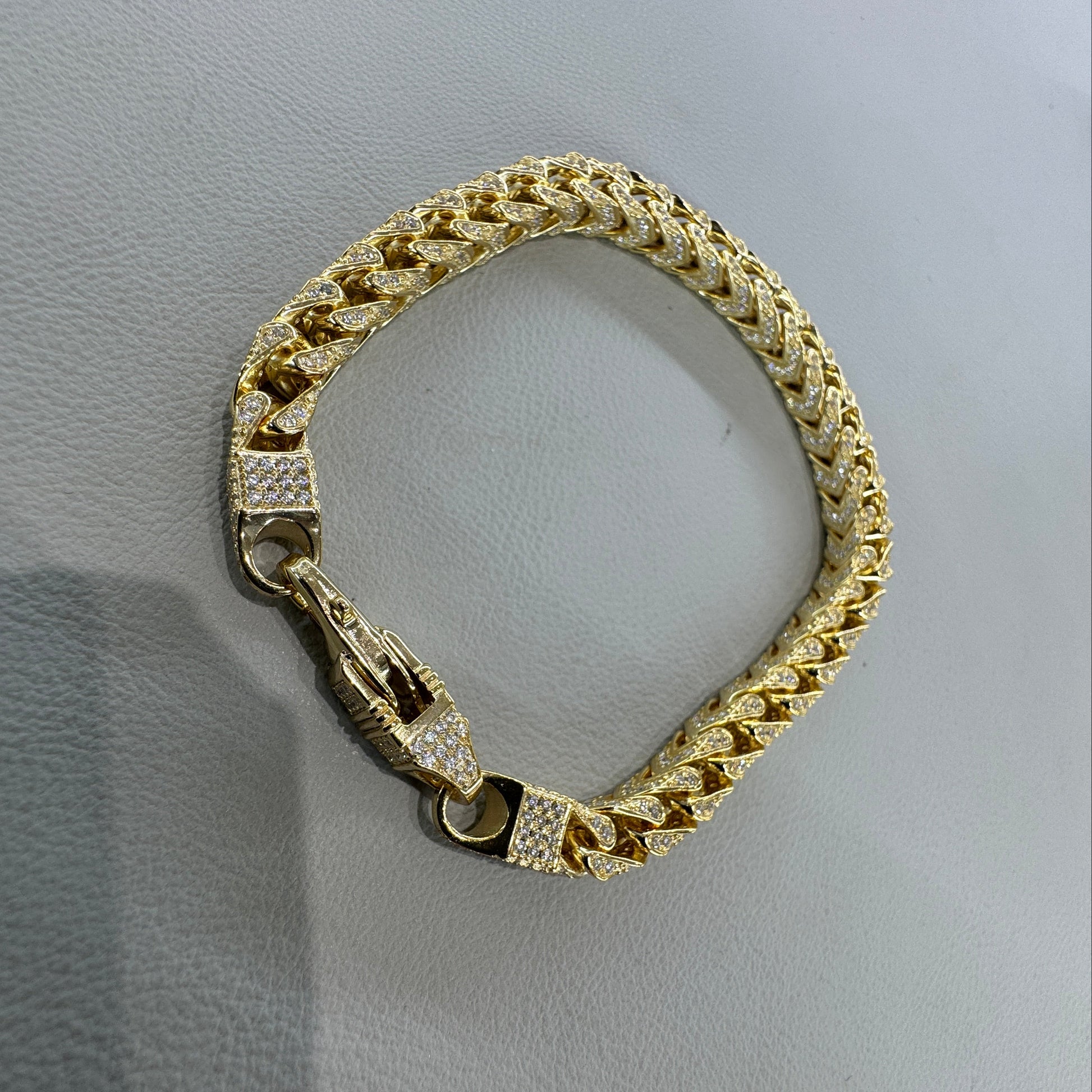 Gold bracelet with diamond accents on a light gray surface