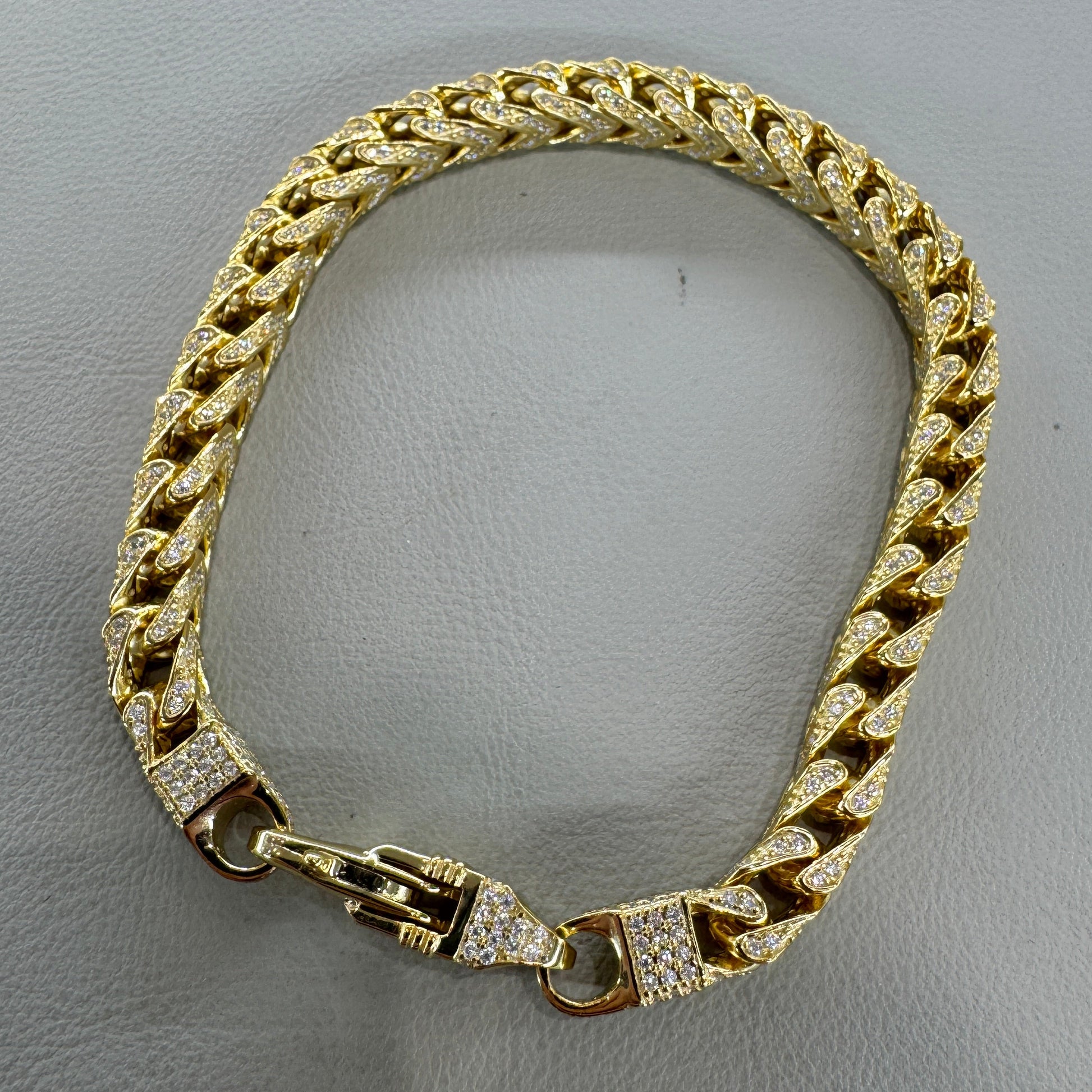 Gold chain bracelet on a gray background