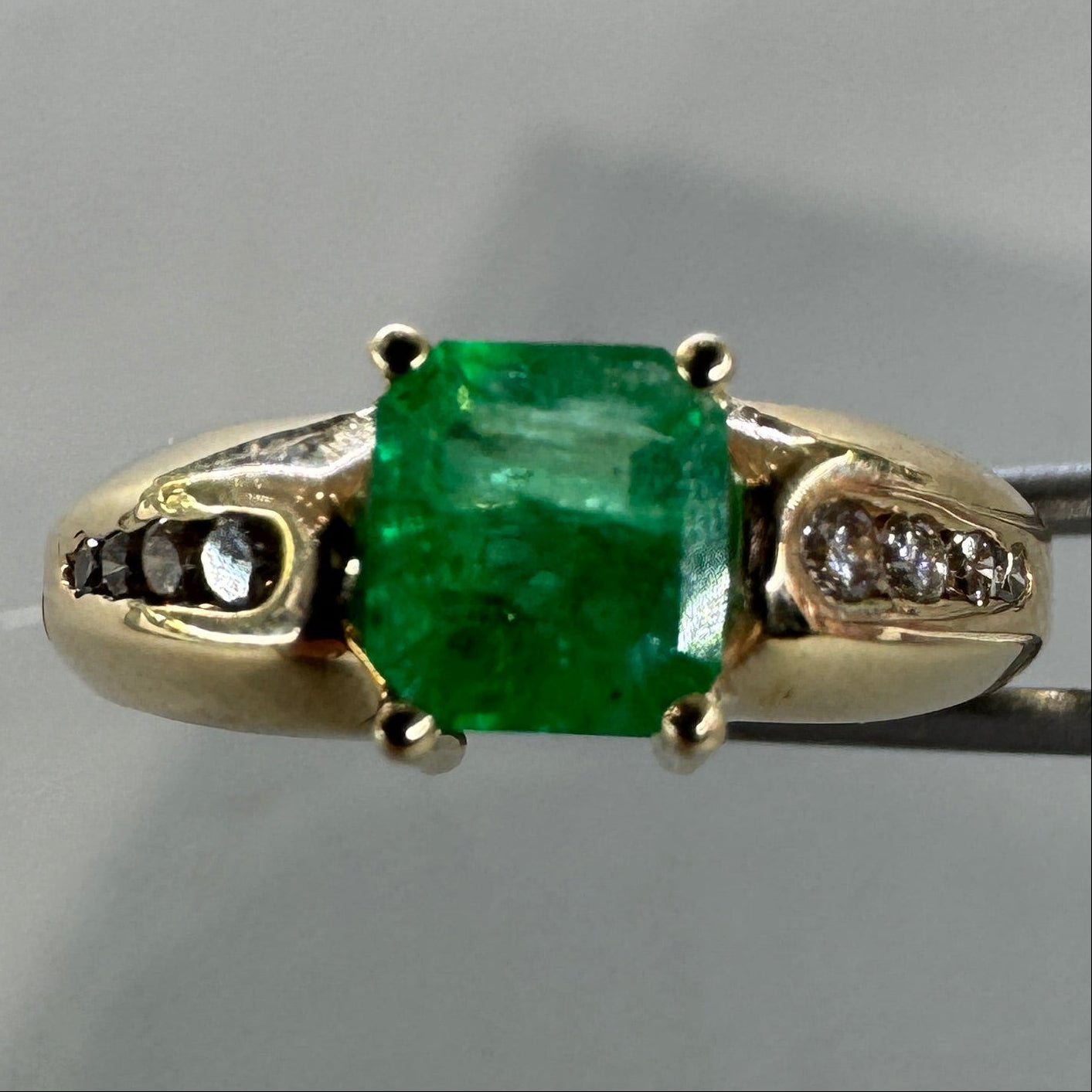 Gold pendant with a green gemstone on a gray background